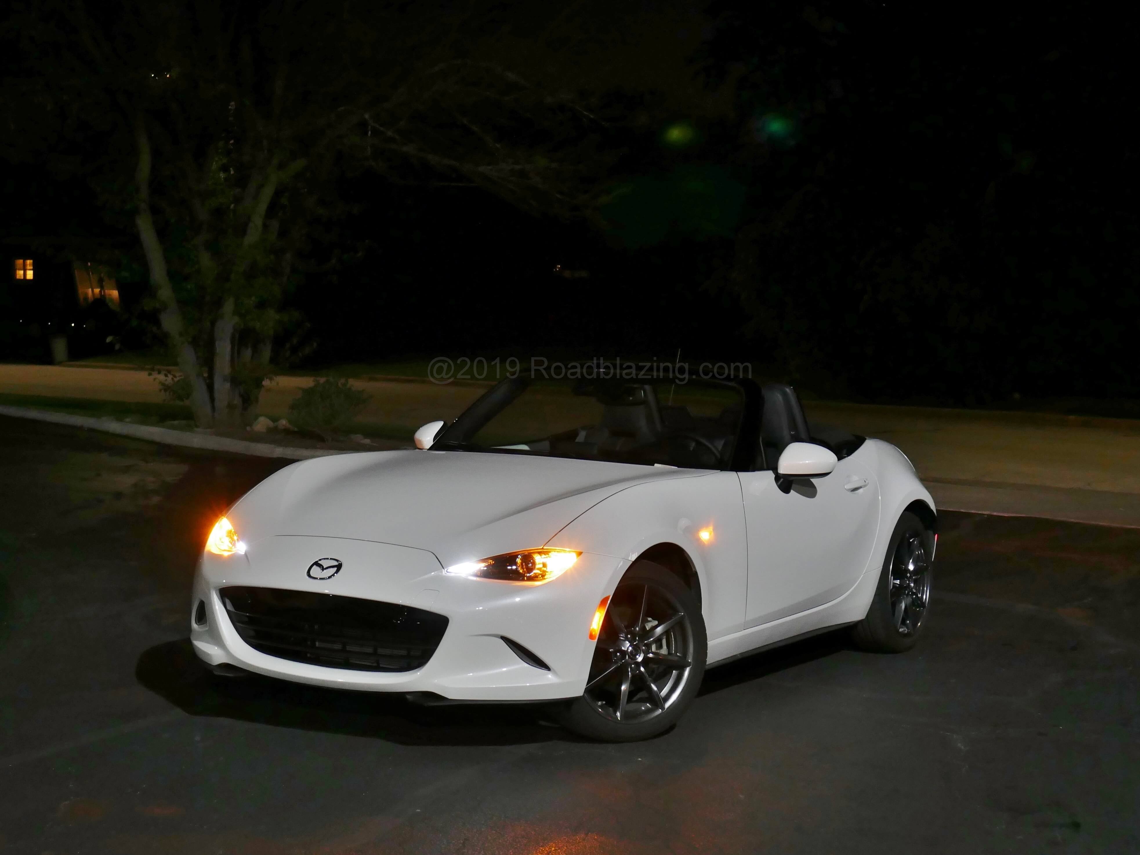 2019 Mazda MX-5 GrandTouring: Whitewater pearl black soft-top roadster, with LED adaptive headlamps and DRLs at night