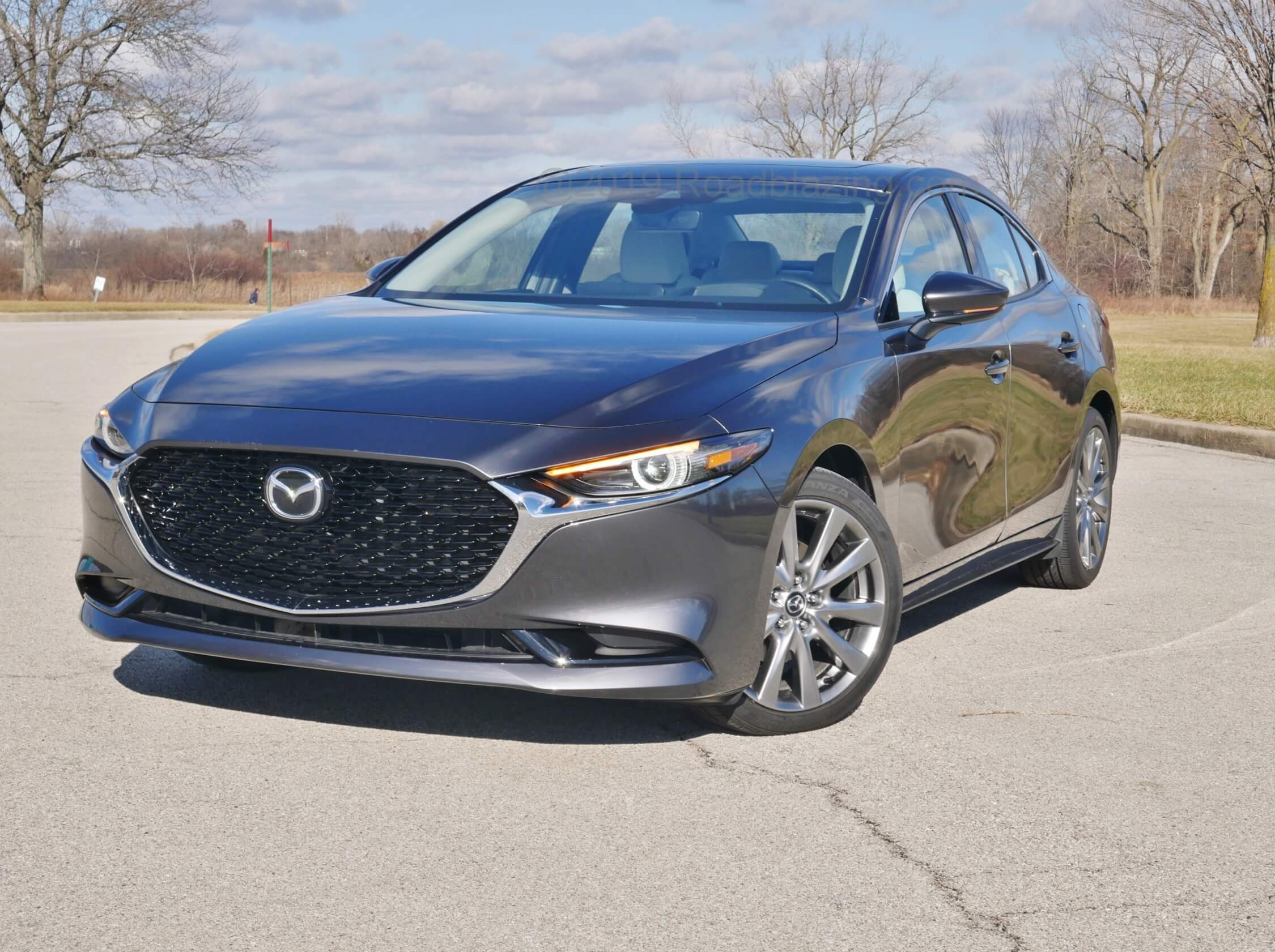 2020 Mazda 3 sedan awd premium: Straight outta Mazda 6 Signature, chrome arms from the shortened pentagonal grille lower bezel extends with arms cradling more drawn prominent amber upper DRL headlamps